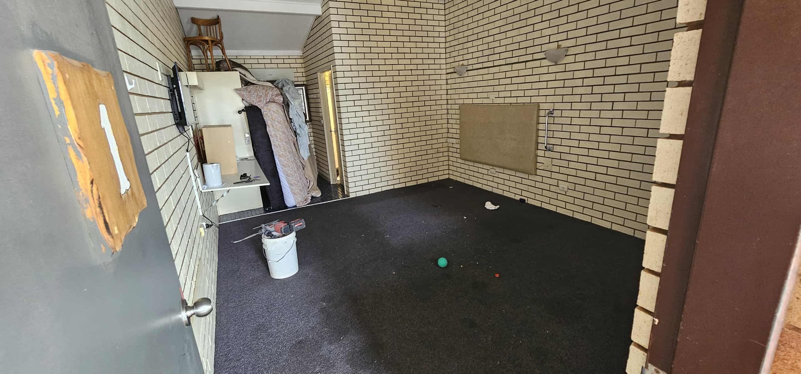 Room before flooring replacement, with dark carpet and furniture stored to one side